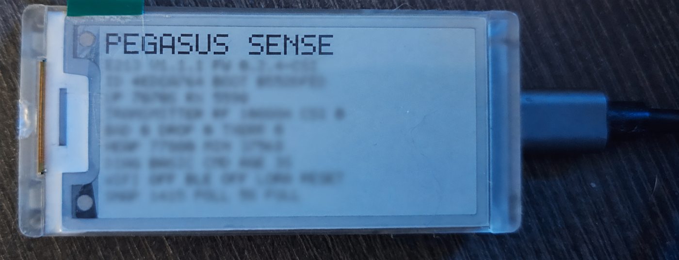 Physical Pegasus Sense ESP32-S3 e-paper device connected by USB and displaying its engineering status screen